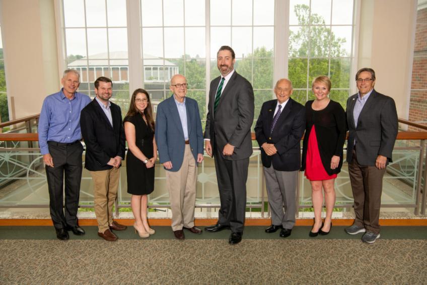 Eight members of the Cutler Scholars Advisory Board pose in front of a window